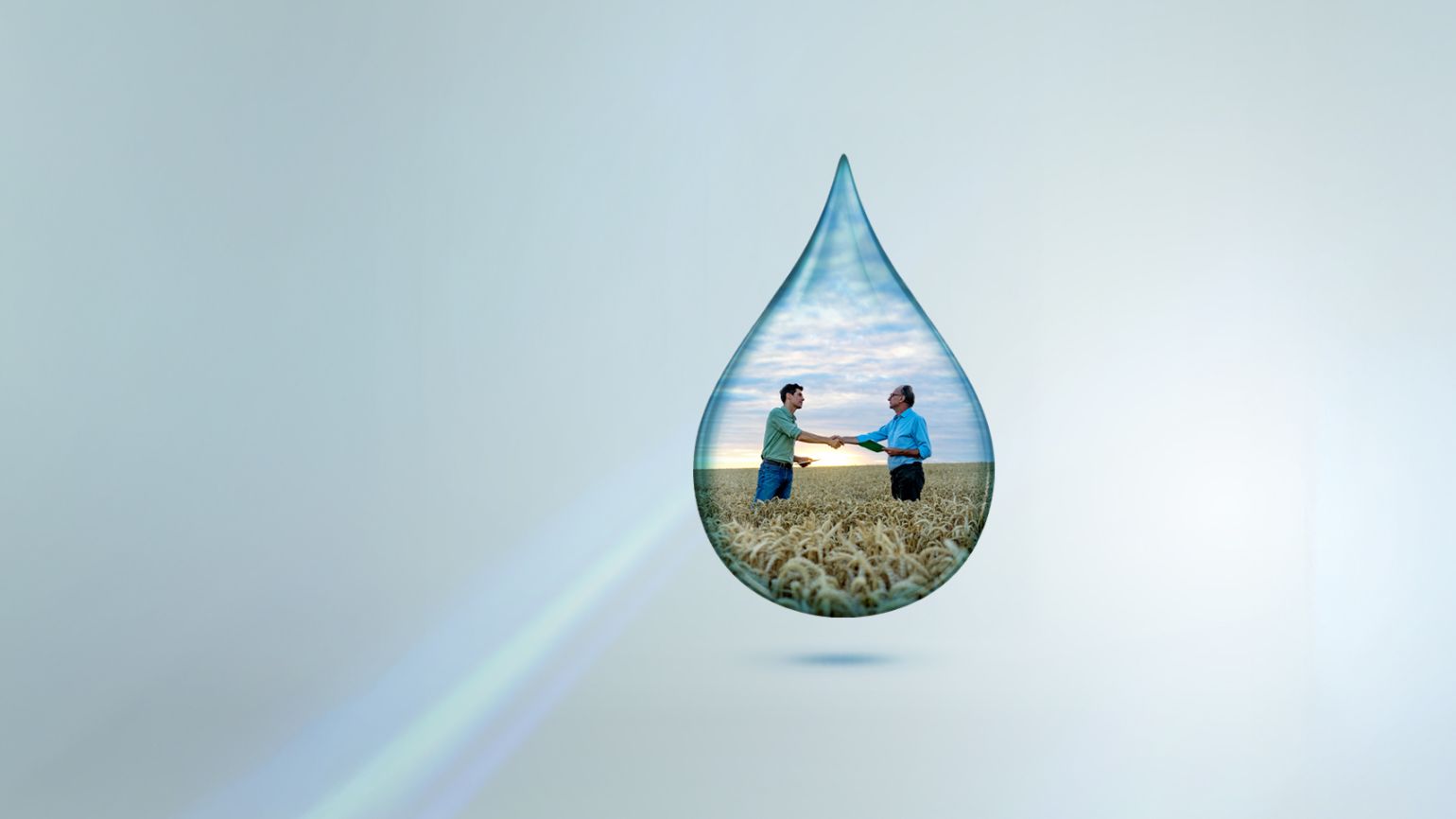    Agricultural professionals shaking hands in a wheat field inside a water droplet, symbolising sustainable farming, water stewardship and agricultural partnerships.